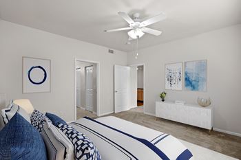 A bedroom with a ceiling fan and attached master bathroom.